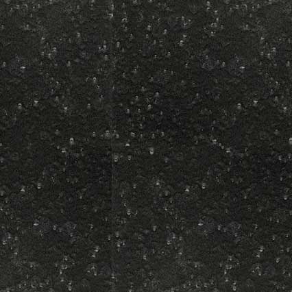 A dark speckled surface texture with small white and light-colored flecks scattered throughout, resembling granite countertop material or terrazzo flooring.